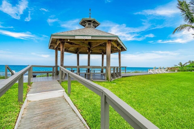 view of dock featuring a gazebo, a water view, and a lawn