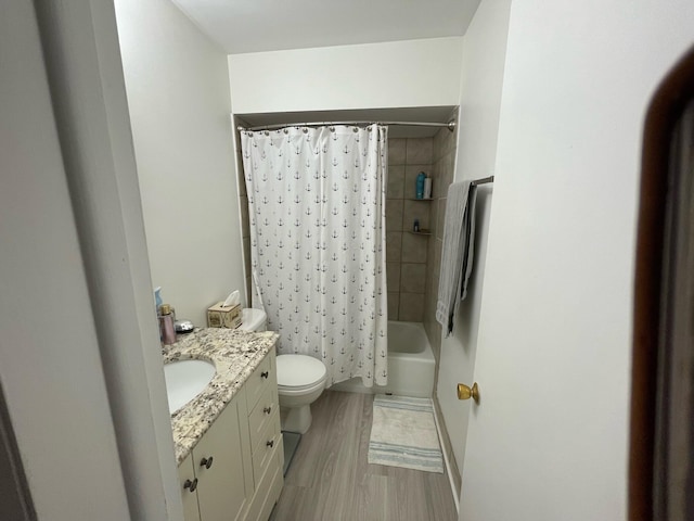 full bathroom featuring hardwood / wood-style floors, vanity, shower / tub combo with curtain, and toilet