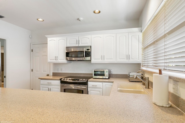 kitchen featuring appliances with stainless steel finishes, white cabinets, and sink