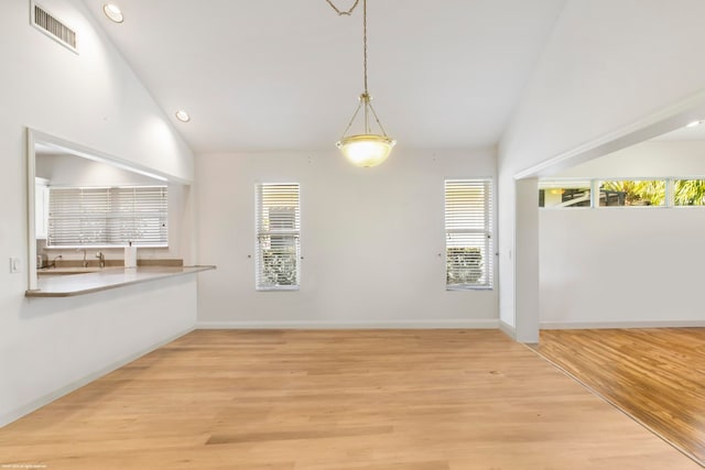 unfurnished dining area with a wealth of natural light, high vaulted ceiling, and light wood-type flooring