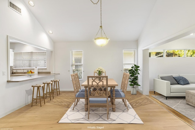 dining area featuring a healthy amount of sunlight, light hardwood / wood-style floors, and high vaulted ceiling