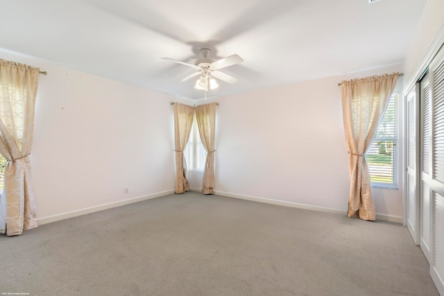 empty room featuring ceiling fan and carpet