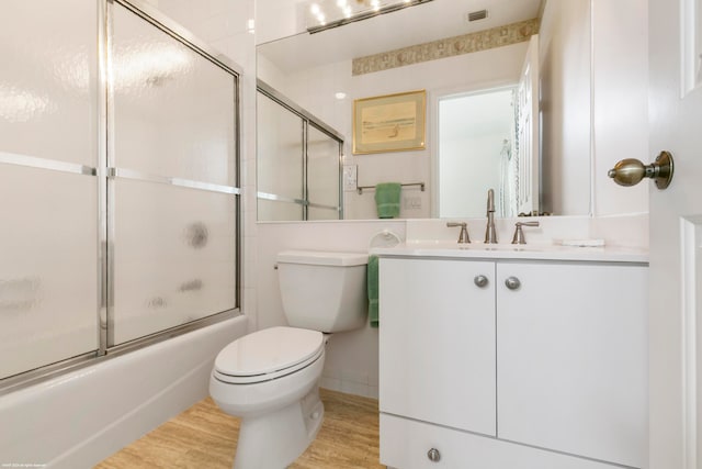 full bathroom featuring wood-type flooring, toilet, combined bath / shower with glass door, and large vanity