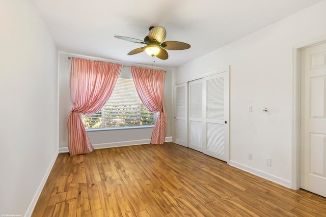 unfurnished bedroom with wood-type flooring, ceiling fan, and a closet