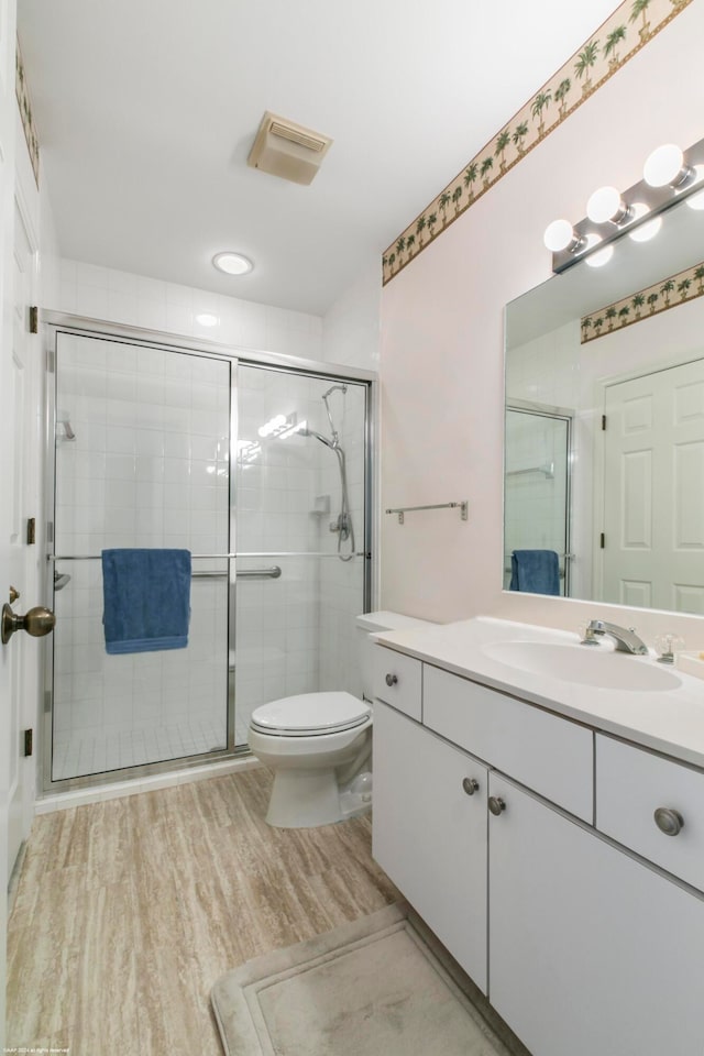 bathroom featuring hardwood / wood-style flooring, an enclosed shower, toilet, and vanity