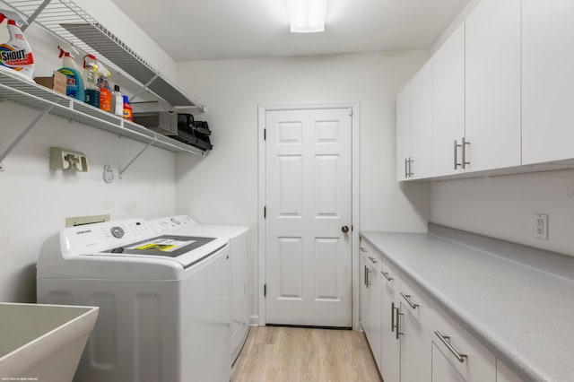 clothes washing area with cabinets, sink, independent washer and dryer, and light wood-type flooring