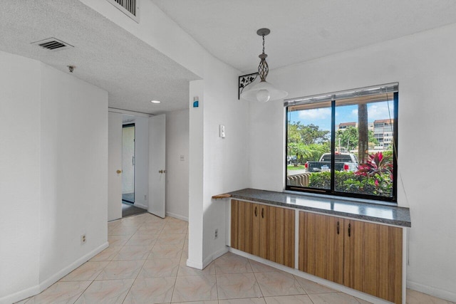 unfurnished room featuring a textured ceiling and light tile flooring