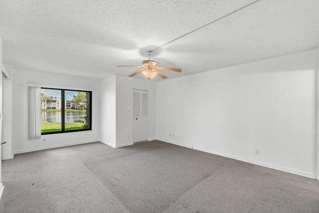 empty room featuring a textured ceiling, ceiling fan, and carpet