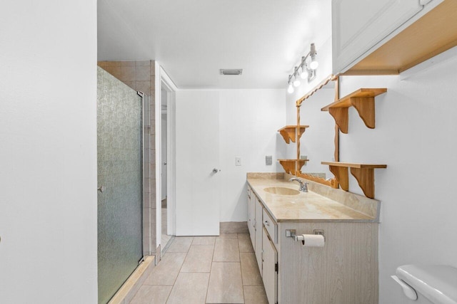 bathroom with vanity with extensive cabinet space, a shower with door, toilet, and tile flooring