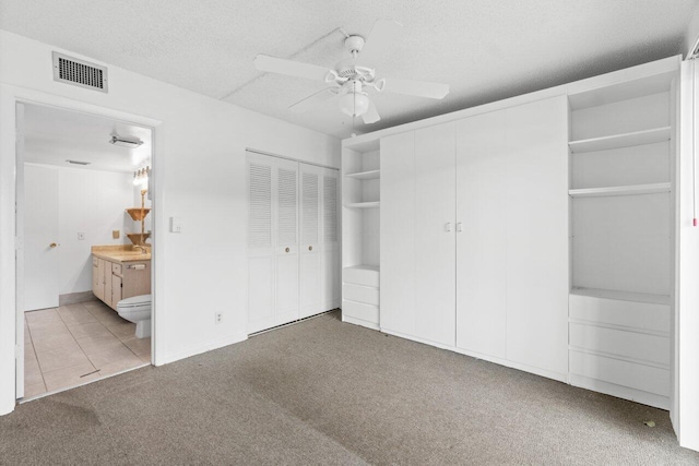 unfurnished bedroom featuring a textured ceiling, ceiling fan, tile floors, and ensuite bathroom