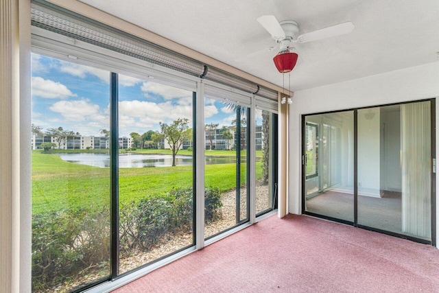 unfurnished sunroom featuring a wealth of natural light, ceiling fan, and a water view