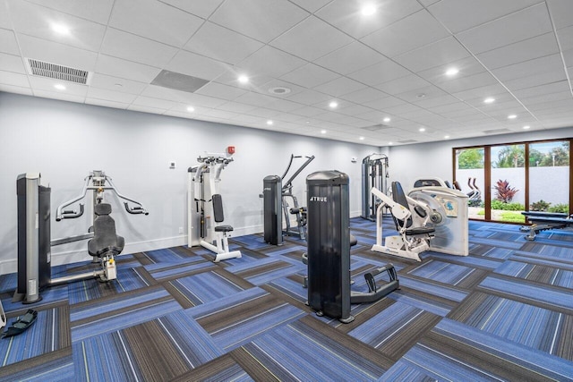 workout area featuring a drop ceiling and dark colored carpet