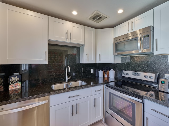 kitchen with tasteful backsplash, appliances with stainless steel finishes, white cabinets, and sink