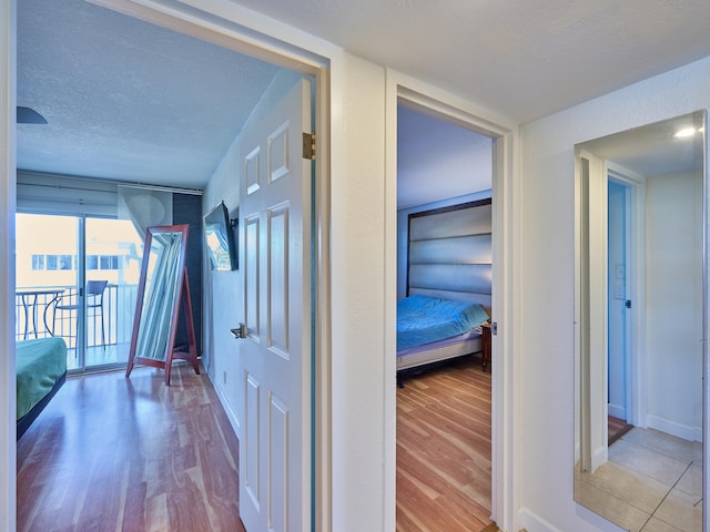 corridor featuring light hardwood / wood-style flooring and a textured ceiling