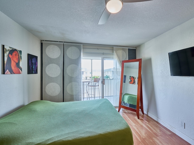 unfurnished bedroom with a textured ceiling, hardwood / wood-style floors, ceiling fan, and access to exterior