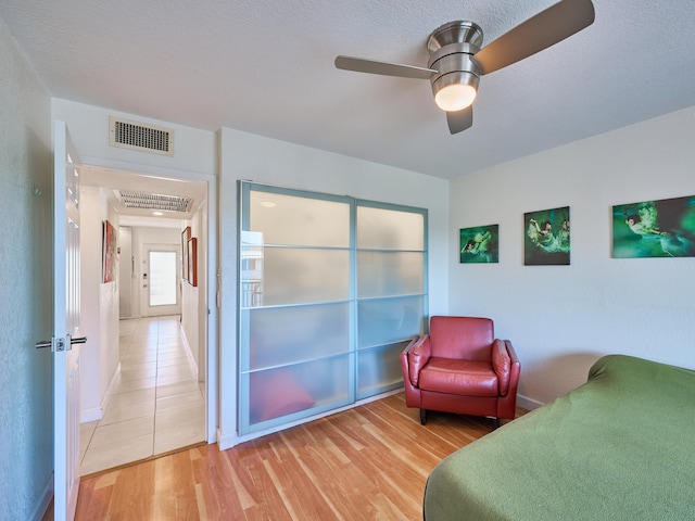 tiled bedroom featuring ceiling fan and a textured ceiling