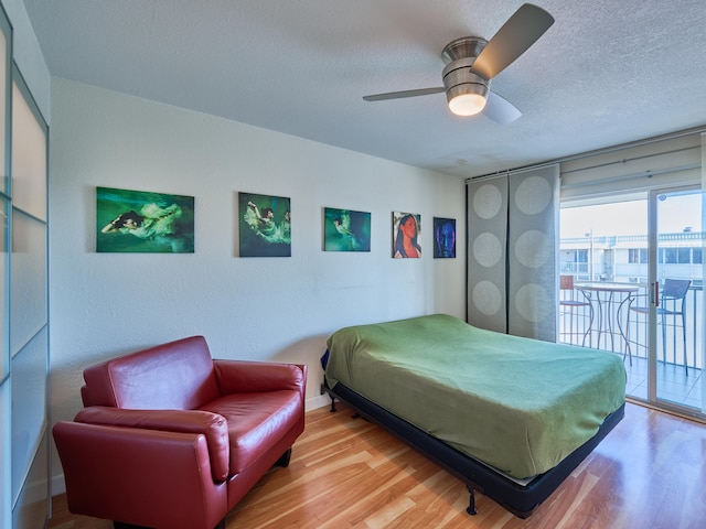 bedroom with a textured ceiling, hardwood / wood-style floors, ceiling fan, and access to exterior