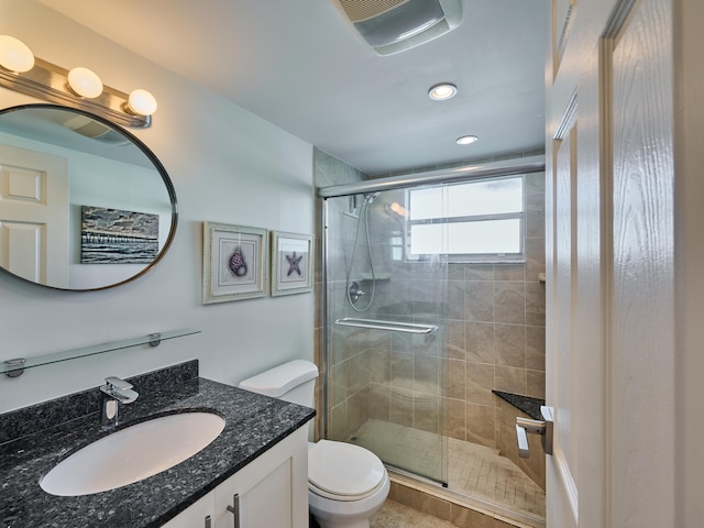 bathroom featuring a shower with door, large vanity, and toilet