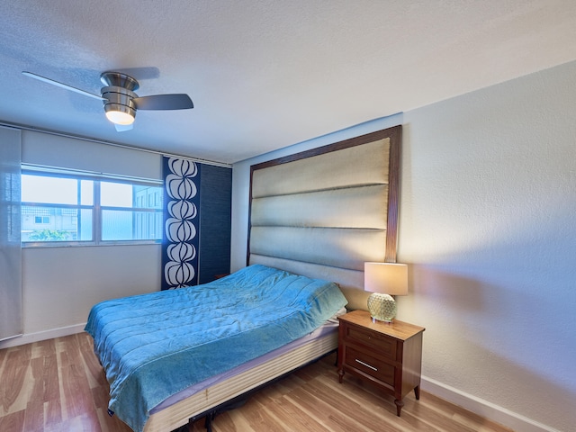 bedroom with wood-type flooring, a textured ceiling, and ceiling fan