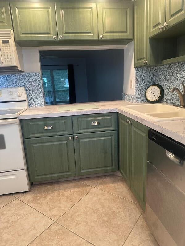 kitchen featuring decorative backsplash, sink, white appliances, and green cabinetry