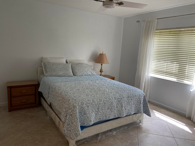 tiled bedroom featuring multiple windows, ceiling fan, and a textured ceiling