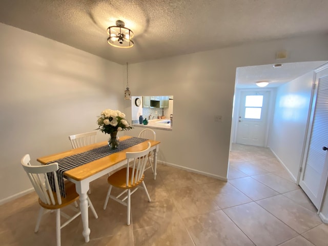 dining area featuring a textured ceiling and light tile patterned flooring