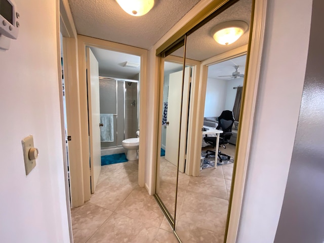 hall featuring light tile patterned floors and a textured ceiling