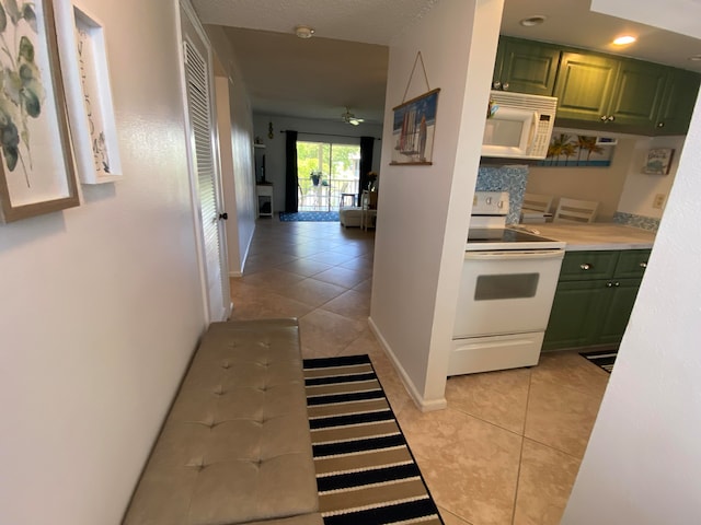 interior space featuring light tile patterned floors, white appliances, green cabinetry, and ceiling fan