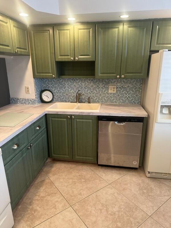 kitchen with backsplash, stainless steel dishwasher, sink, light tile patterned floors, and white fridge with ice dispenser