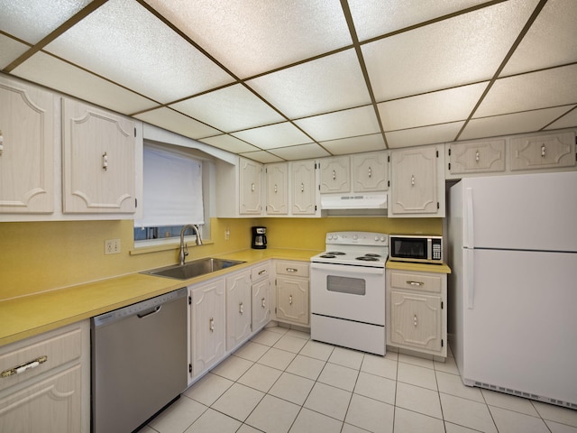 kitchen featuring white cabinets, stainless steel appliances, sink, light tile floors, and a paneled ceiling