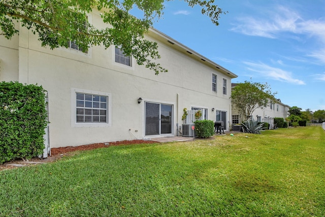 back of property featuring central AC unit and a lawn