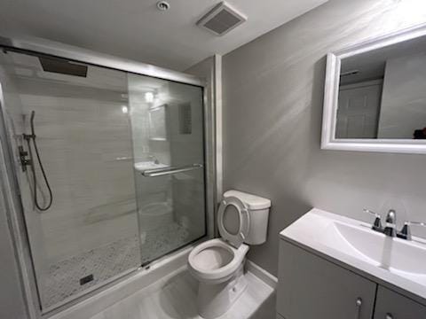 bathroom with a shower with door, toilet, and large vanity