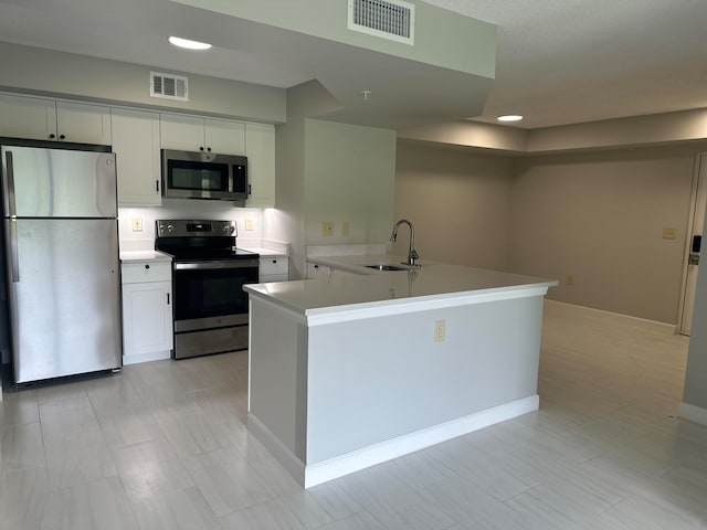 kitchen featuring appliances with stainless steel finishes, a center island, light tile floors, sink, and white cabinetry