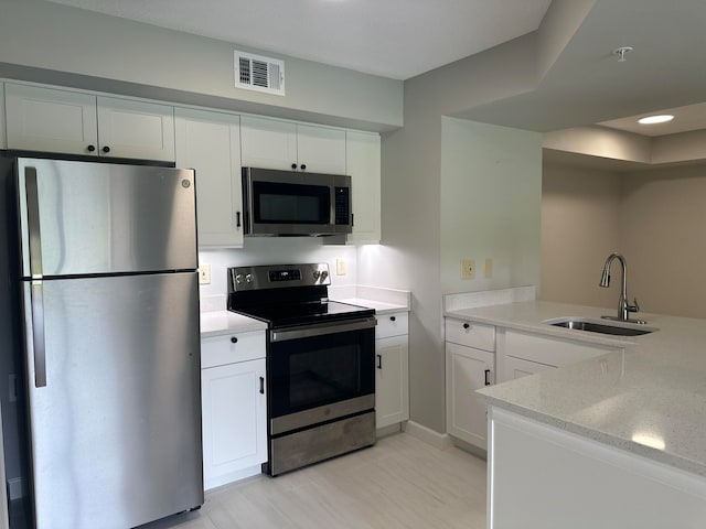 kitchen featuring white cabinets, sink, stainless steel appliances, and light stone counters