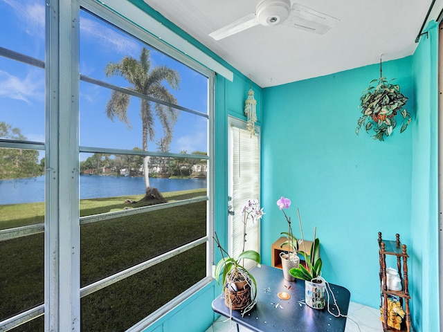 sunroom with ceiling fan and a water view