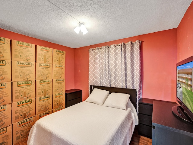 bedroom with dark hardwood / wood-style flooring and a textured ceiling