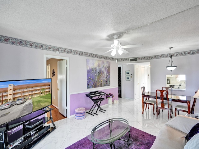 living room featuring a textured ceiling, ceiling fan, and light tile floors