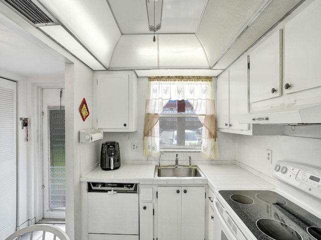 kitchen with sink, dishwasher, white cabinetry, stove, and tile countertops