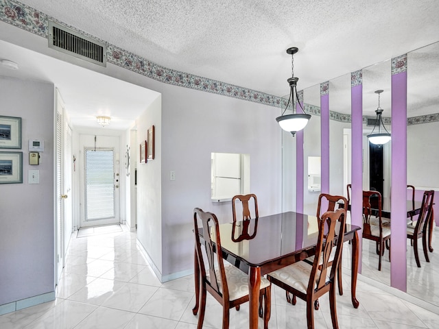 dining area with light tile floors and a textured ceiling