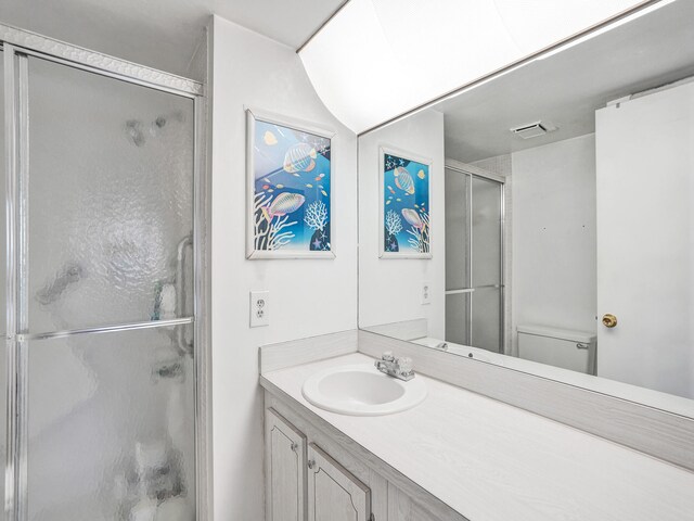 bathroom with vanity with extensive cabinet space, toilet, and walk in shower