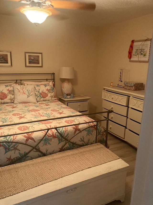 bedroom with a textured ceiling, ceiling fan, and hardwood / wood-style flooring