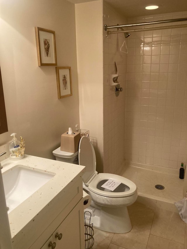 bathroom featuring tile flooring, tiled shower, vanity, and toilet