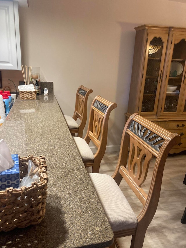 interior space featuring a kitchen breakfast bar, stone counters, and hardwood / wood-style floors