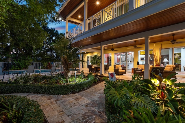 patio terrace at dusk featuring outdoor lounge area, a balcony, and ceiling fan