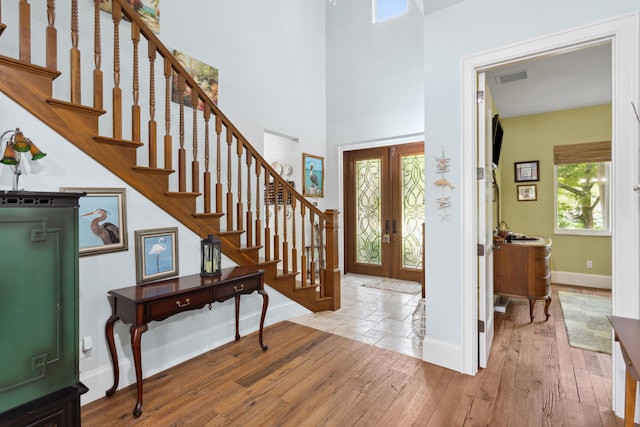 foyer with french doors, light hardwood / wood-style floors, and a high ceiling