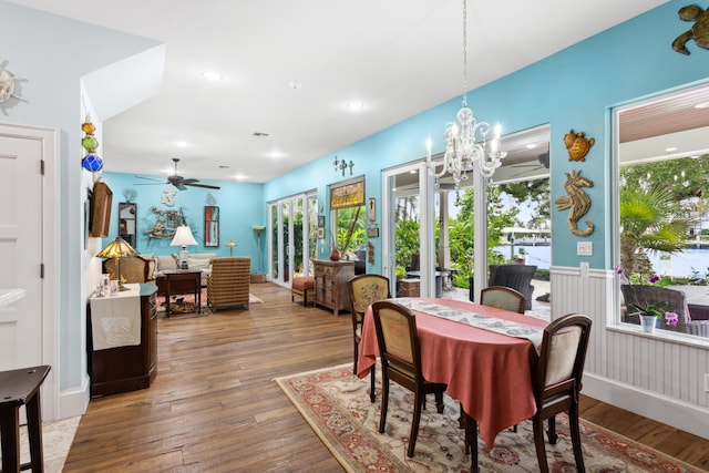 dining space with ceiling fan with notable chandelier and wood-type flooring