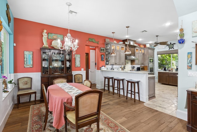 dining space with hardwood / wood-style floors and ceiling fan with notable chandelier