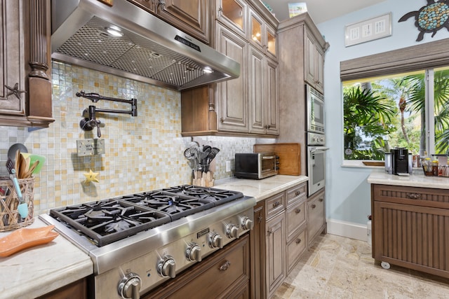 kitchen featuring backsplash, light stone counters, and appliances with stainless steel finishes