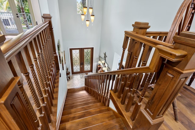 stairs featuring french doors, hardwood / wood-style floors, and a notable chandelier