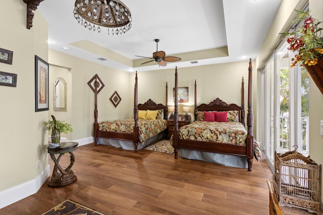 bedroom featuring hardwood / wood-style flooring, ceiling fan, and a tray ceiling